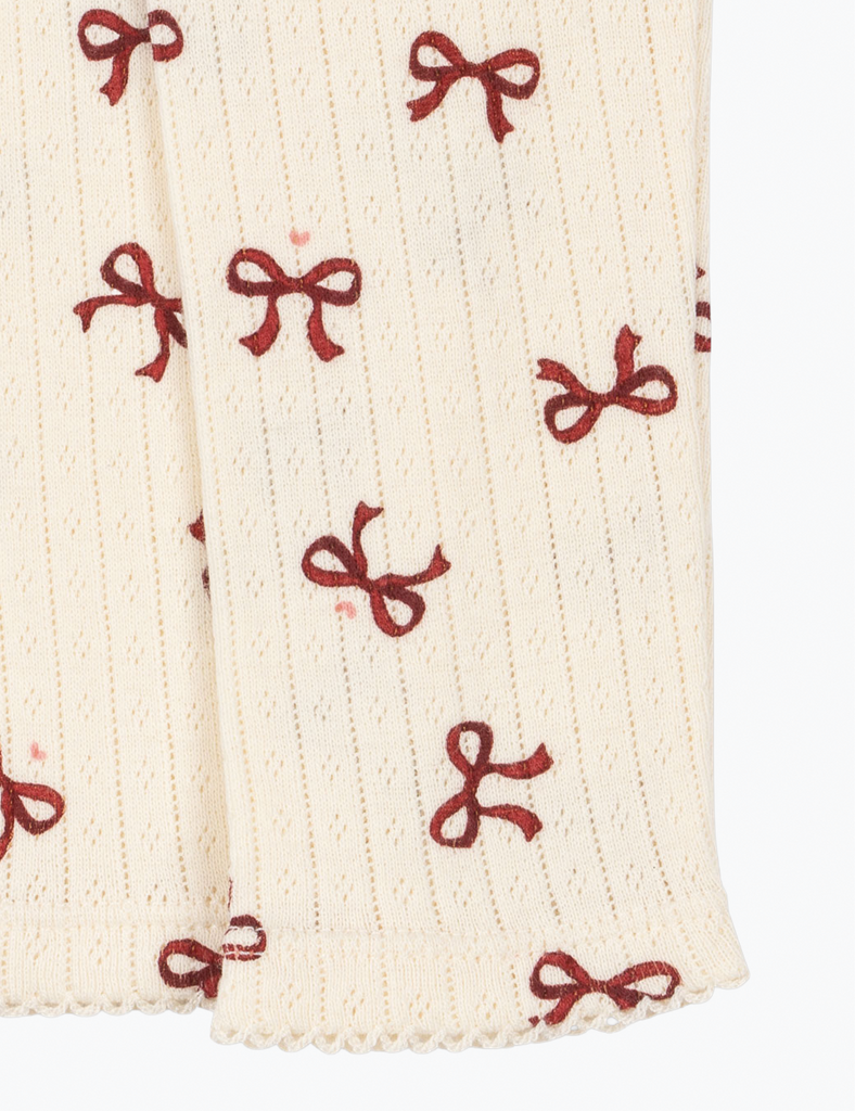 Close-up of cream-colored fabric with red bow pattern