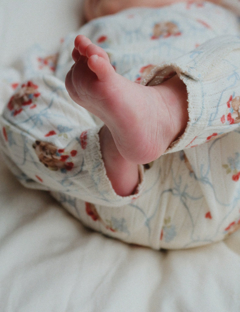 Close-up of a baby's foot in puppy patterned romper on a soft surface