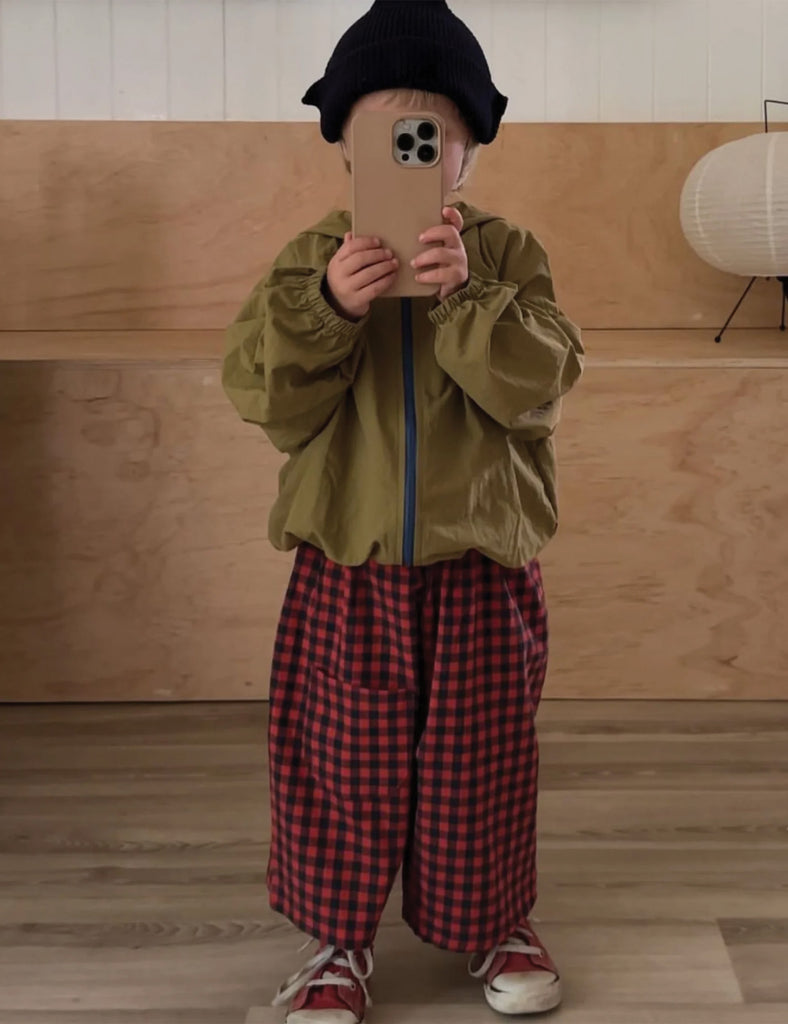 Child taking a selfie in a room with wooden walls and a white ceiling light fixture.