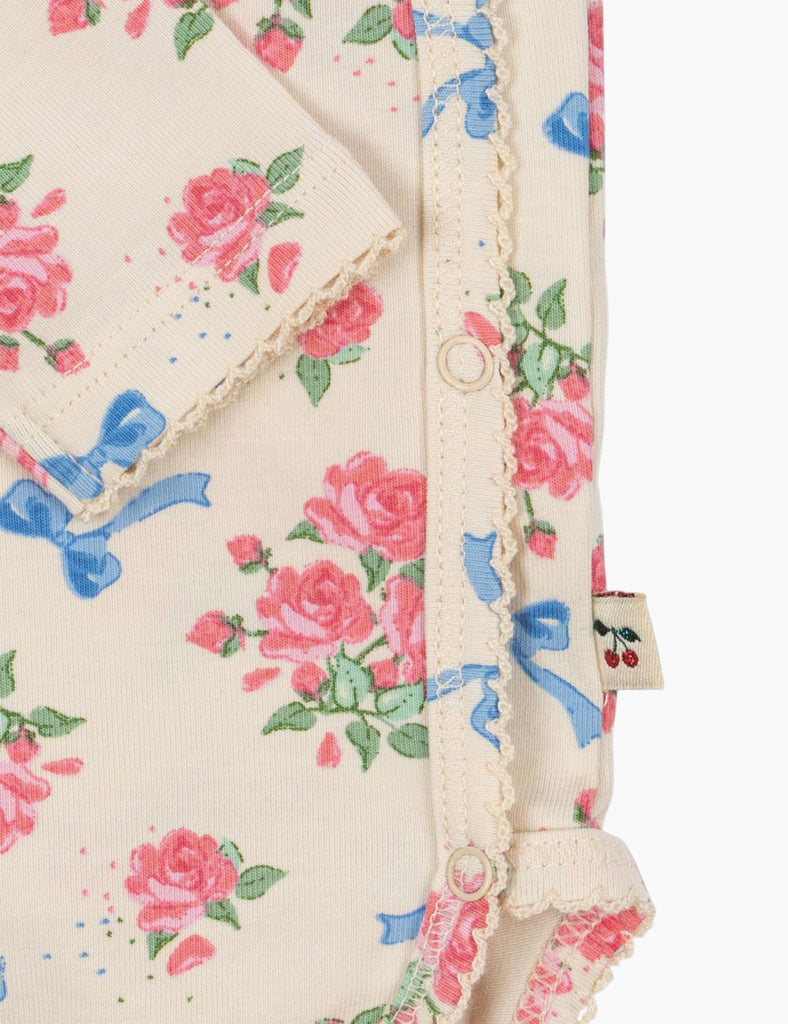 Floral patterned fabric with pink roses and blue bows on a beige background