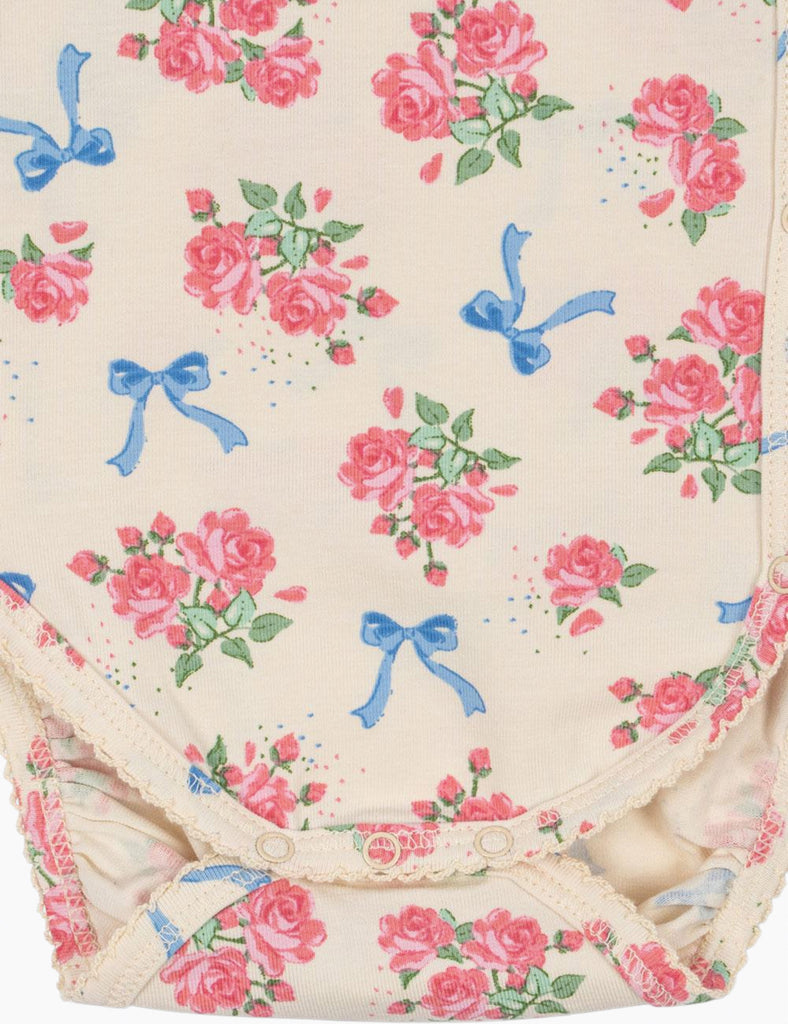 Floral patterned fabric with pink roses and blue bows on a beige background