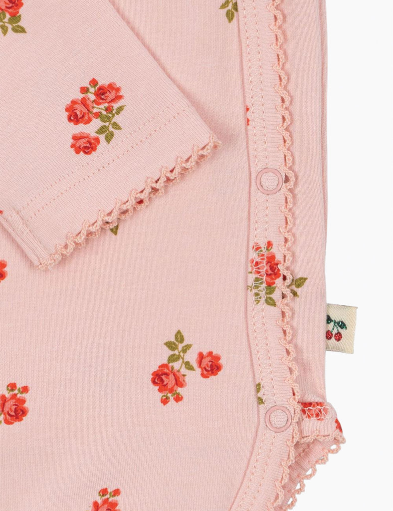 Close-up of a pink garment with floral patterns and lace trim on a white background.