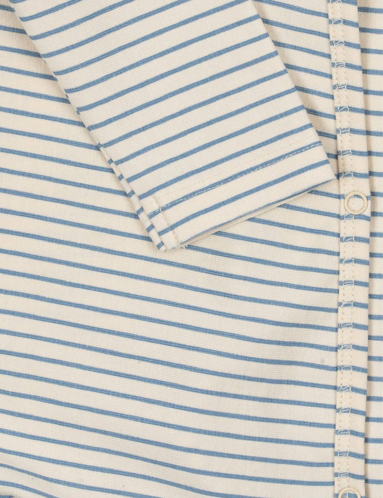 Close-up of a folded shirt with blue and white stripes on a matching fabric background.
