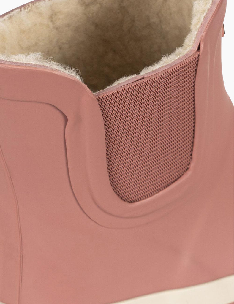 Close-up of a pink shoe with a textured sole and white lining.