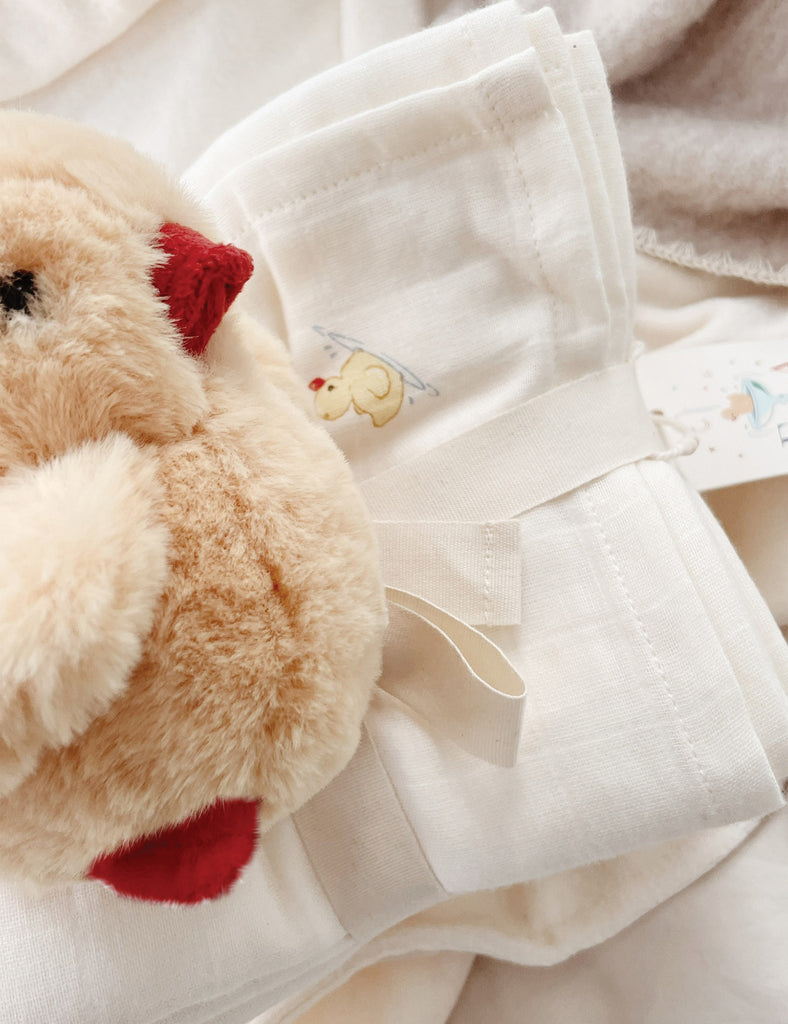 Close-up of a plush toy and white fabric with embroidered designs.