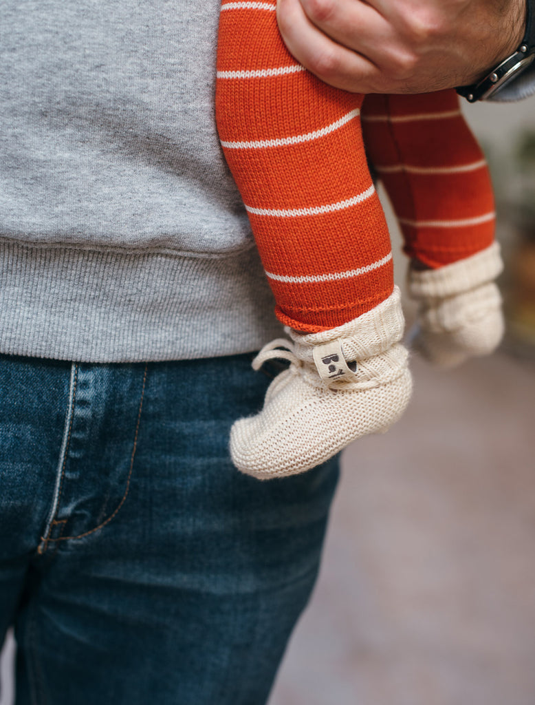 Orion baby booties in milk flat lifestyle image.