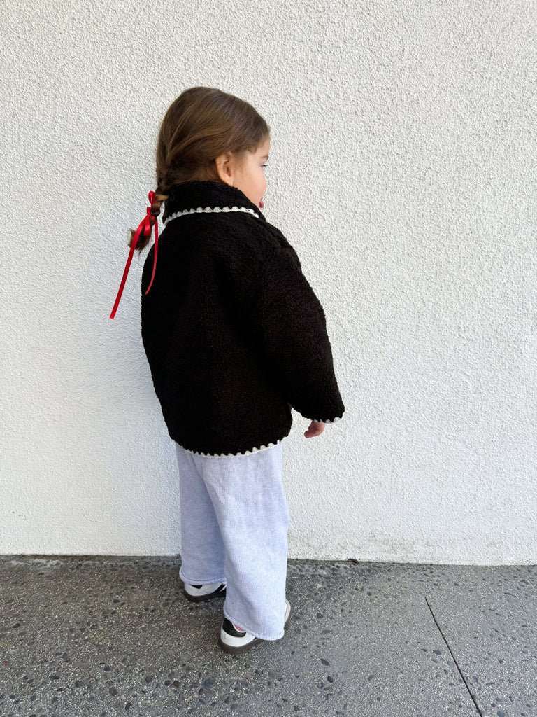 This is an image of a litte girl wearing the paddy faux sherpa jacket in jet black. 