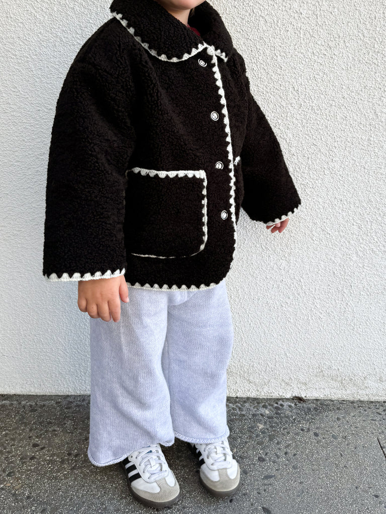 This is an image of a litte girl wearing the paddy faux sherpa jacket in jet black. 