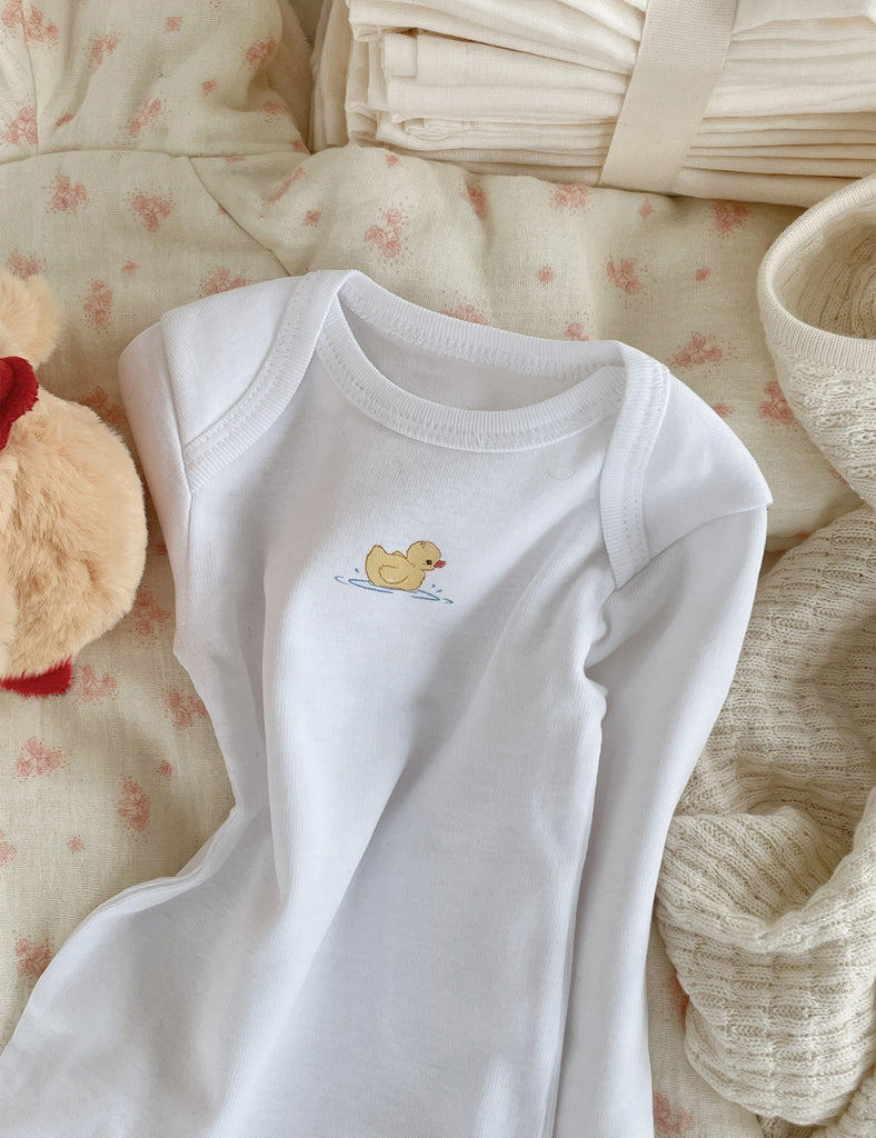 White baby onesie with a duck design on a soft, textured background