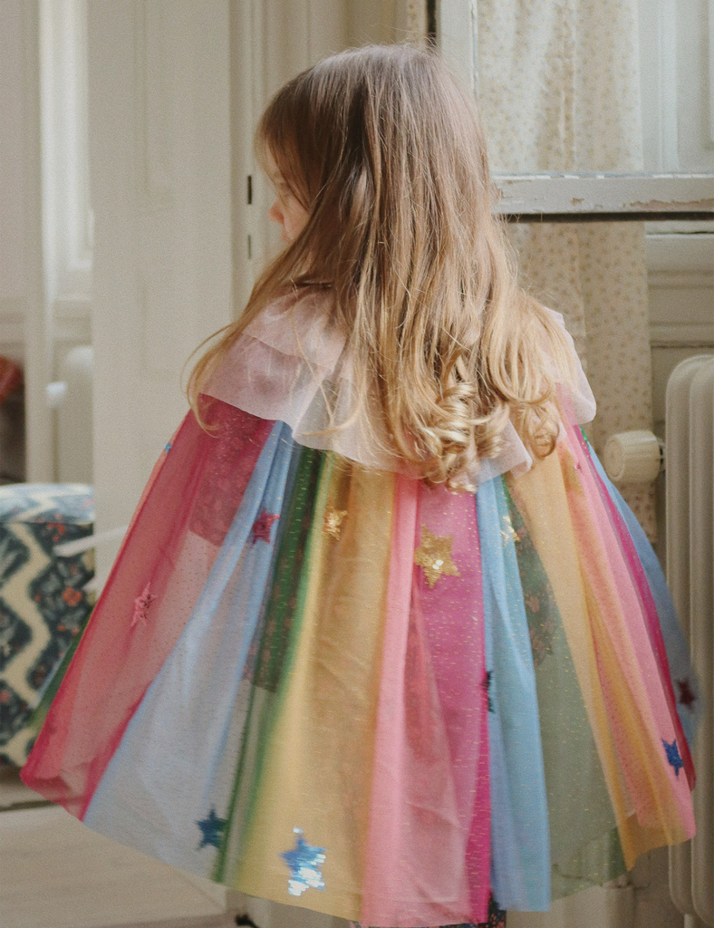 Child wearing a colorful dress with star patterns indoors.