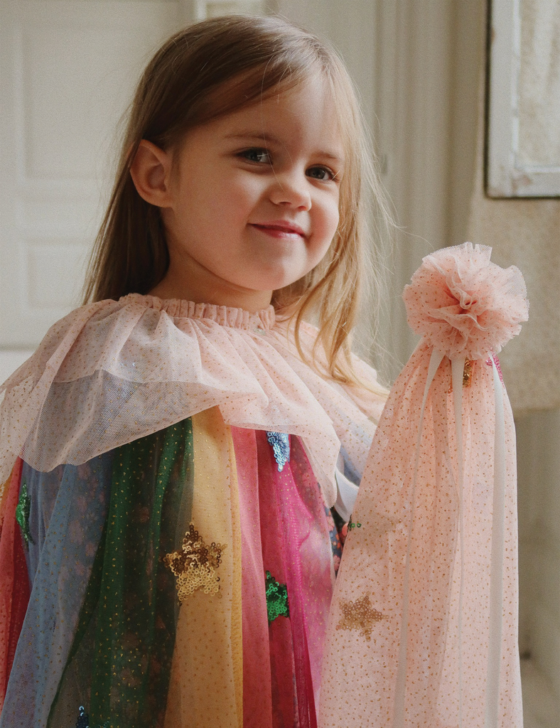 Young girl holding a colorful scarf with star patterns indoors.