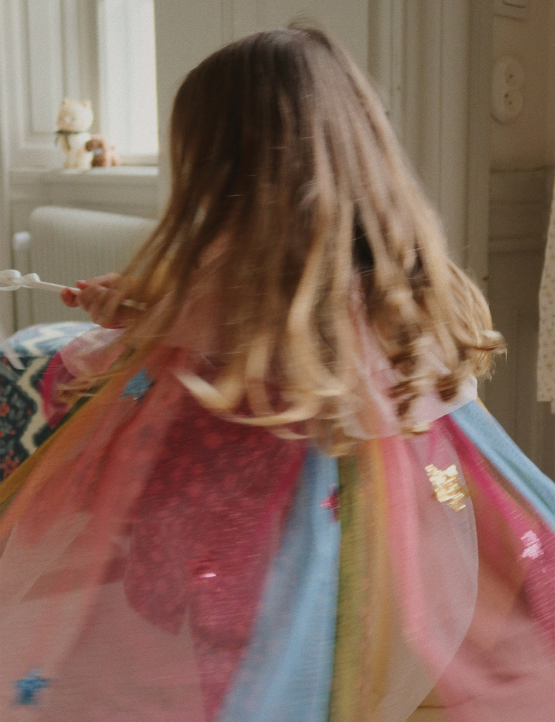 Child in a colorful dress with long hair in a room.