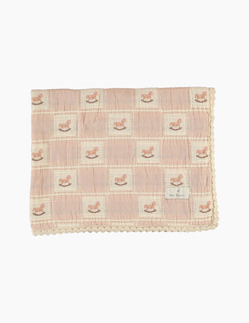 Pink checkered blanket with embroidered rocking horses on a white background