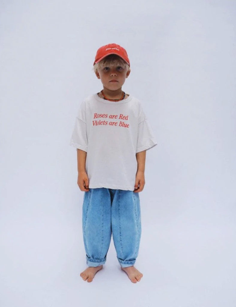Image of a little boy wearing a white tee shirt with red print, jeans and a red baseball cap.