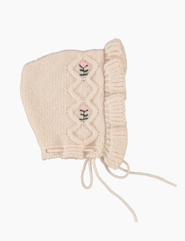 Knitted baby bonnet with floral embroidery on a white background