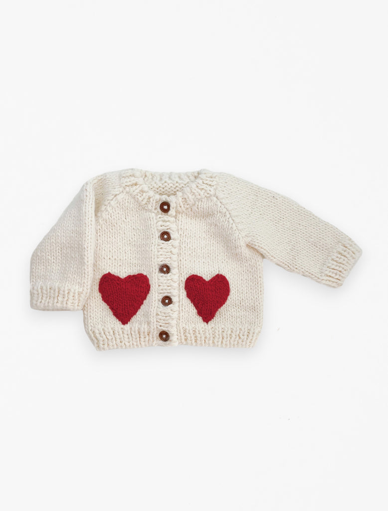 Red heart cardigan in cream flat lay image.