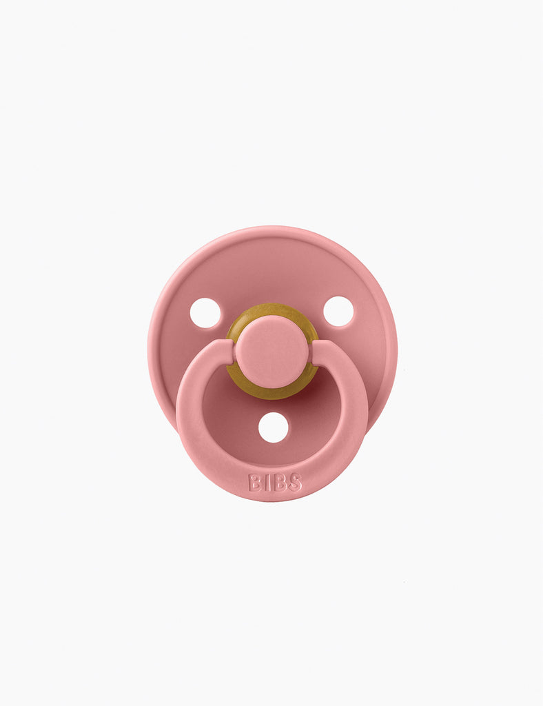 Pink baby pacifier on a white background