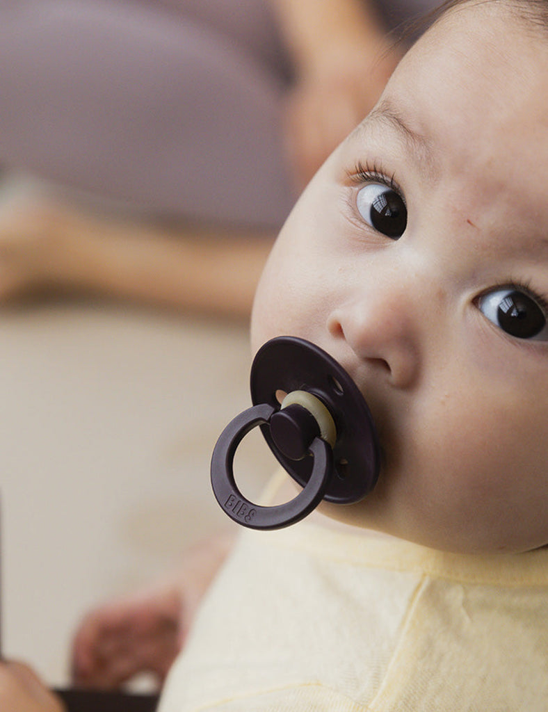 Baby with a pacifier in a blurred indoor setting