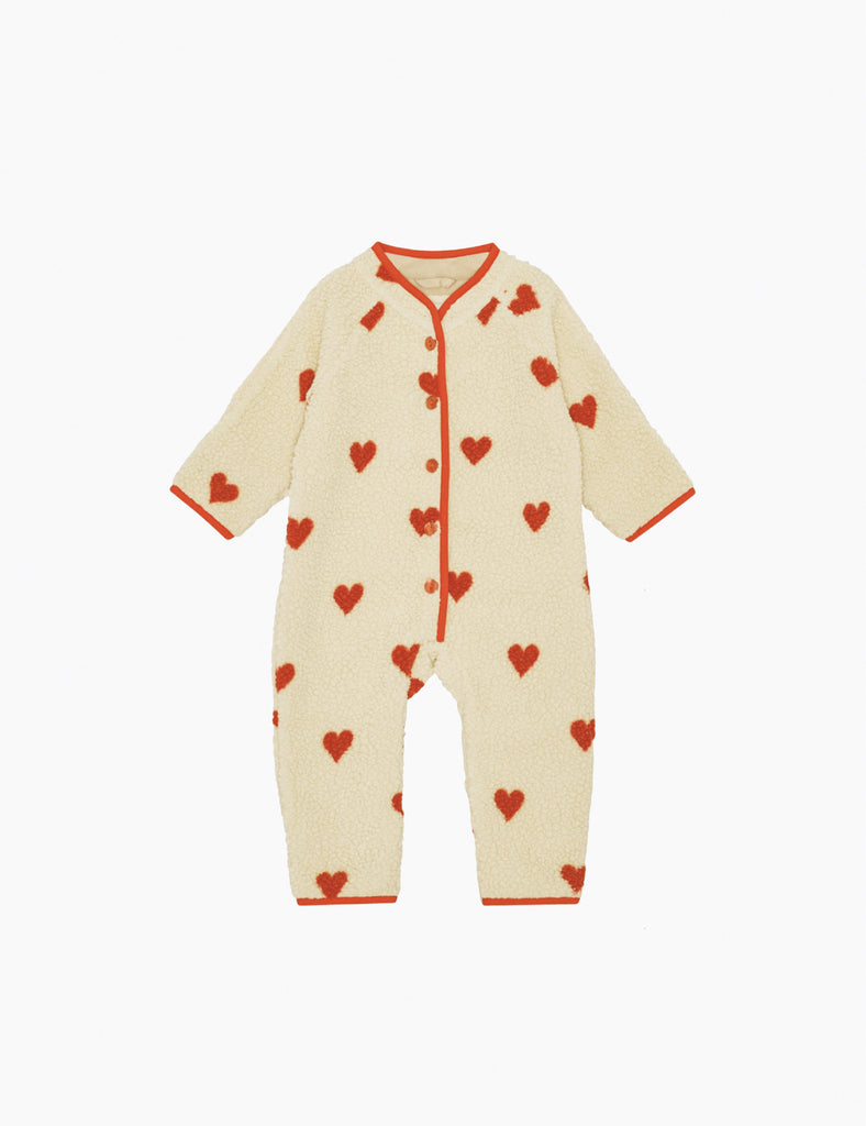 Beige baby onesie with red heart patterns on a white background