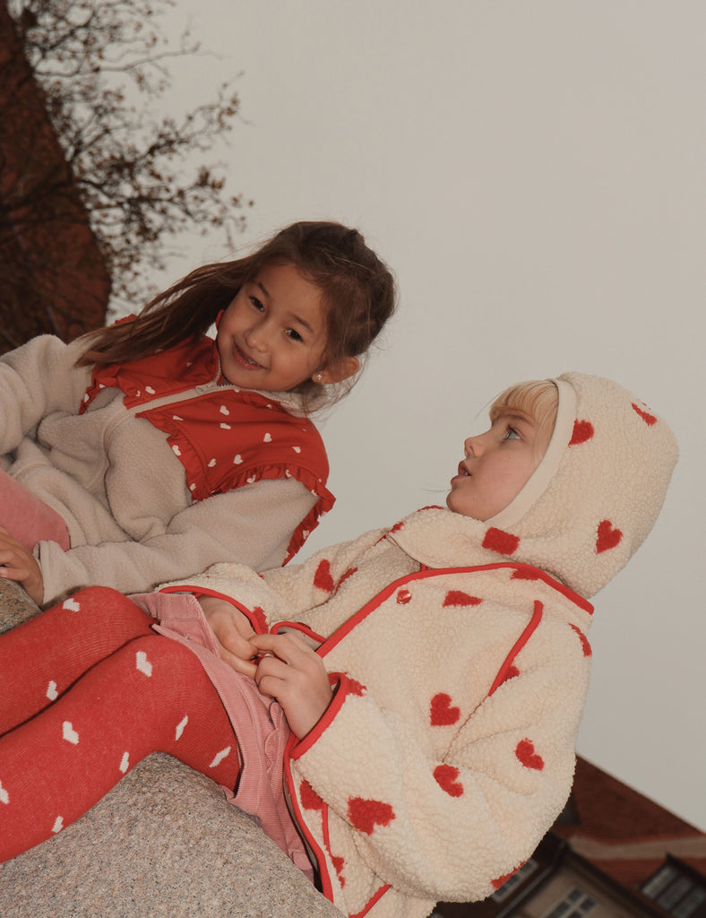 Two children in matching heart-patterned outfits sitting together.