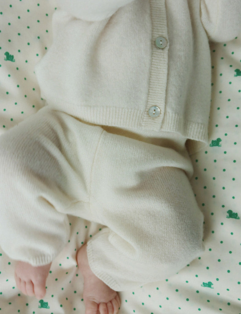 Baby in cream-colored outfit on a polka dot blanket
