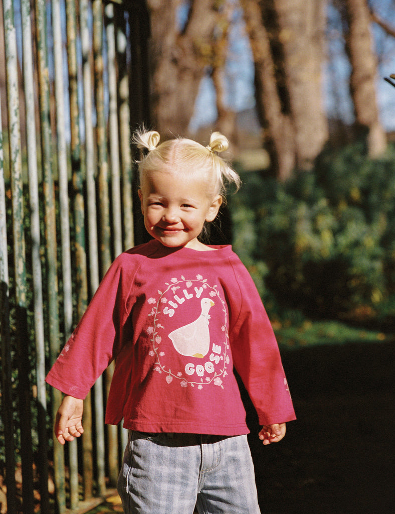 Child wearing a red shirt with a graphic design outdoors