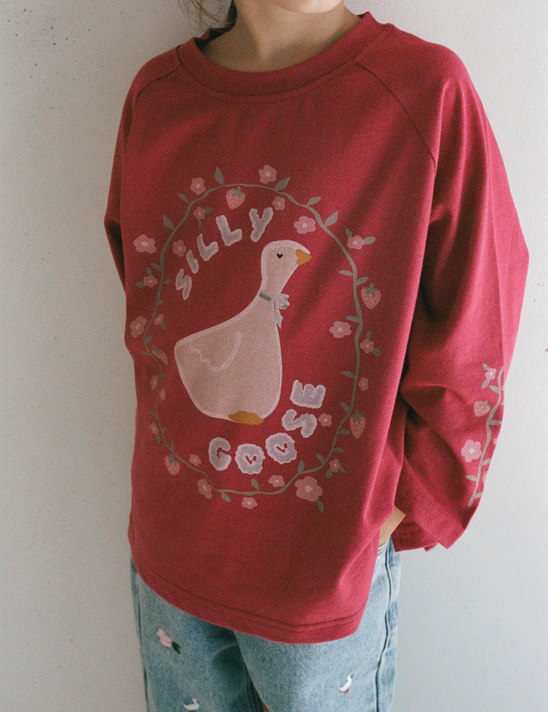 Red sweatshirt with a cartoon duck and text design on a plain background