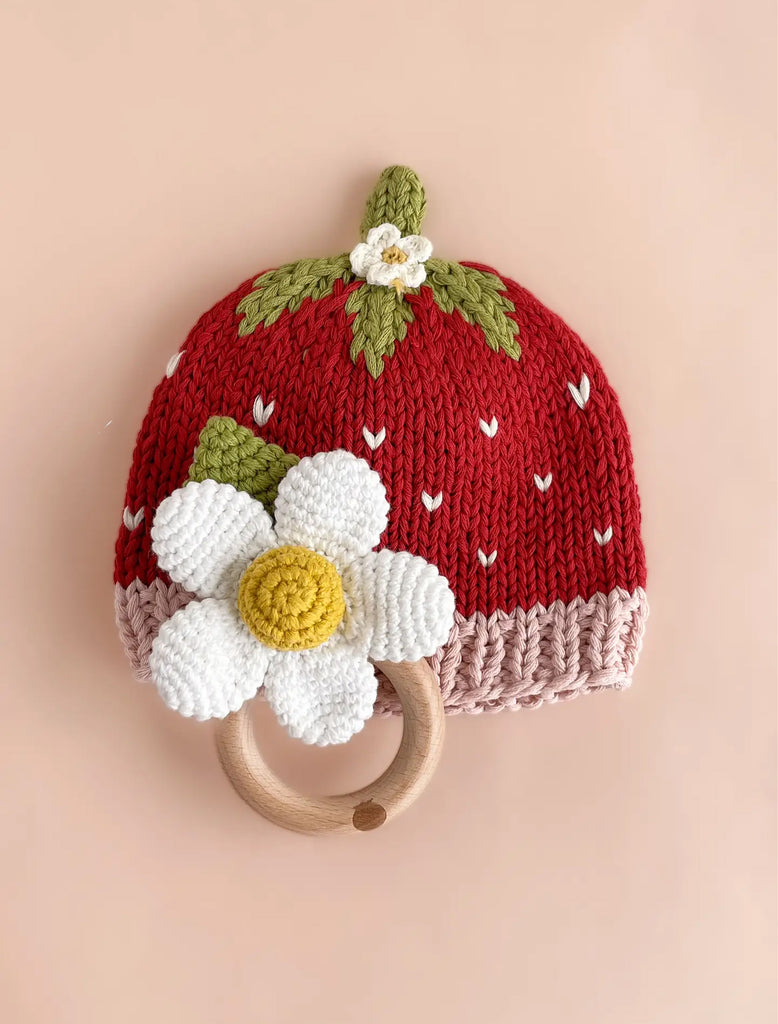 Image of a strawberry knit beanie with blush trim, green stem and hand crocheted flower on top.