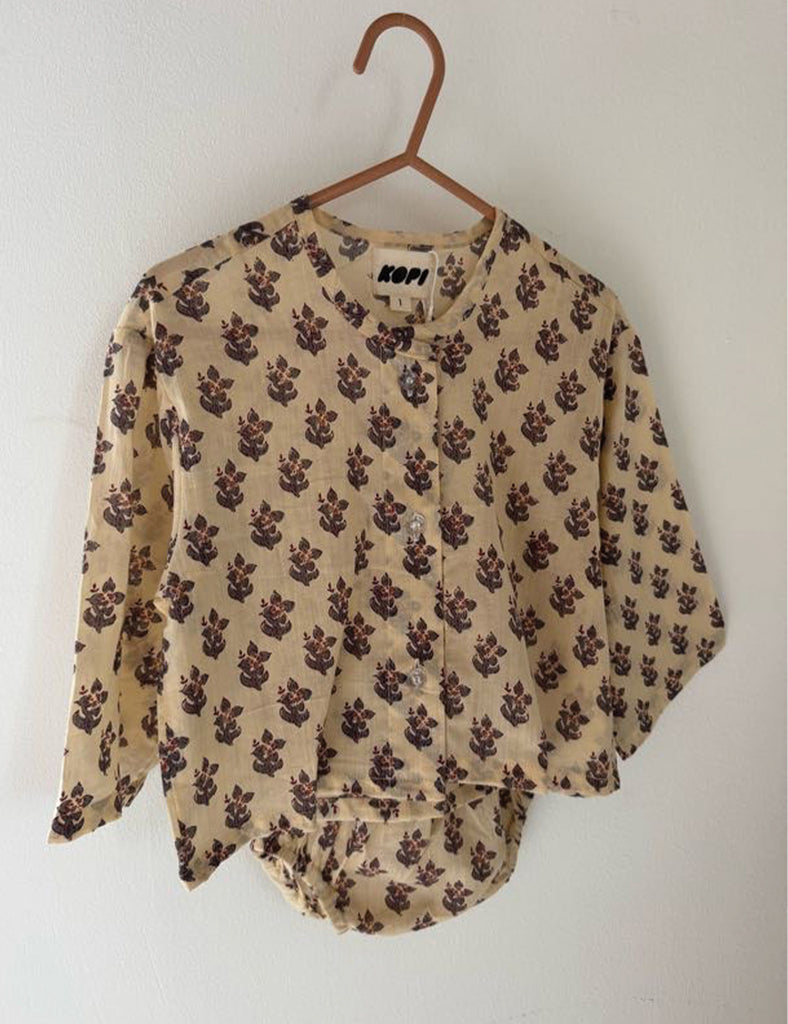 Floral-patterned blouse on a hanger against a white background
