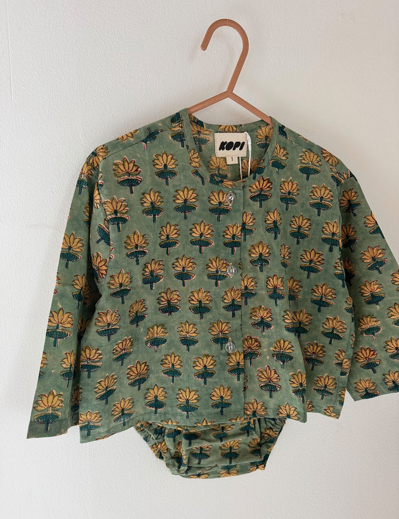Green baby outfit with floral pattern on a hanger against a white background