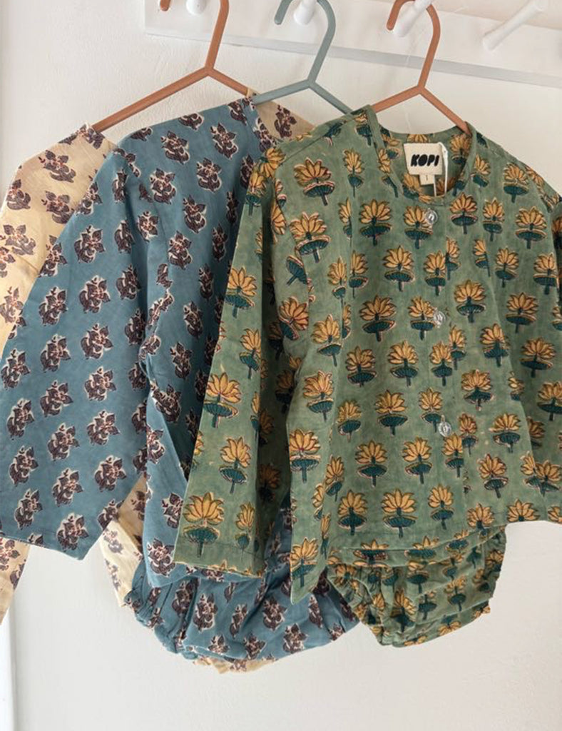 Two patterned baby sets hanging on hangers against a white background