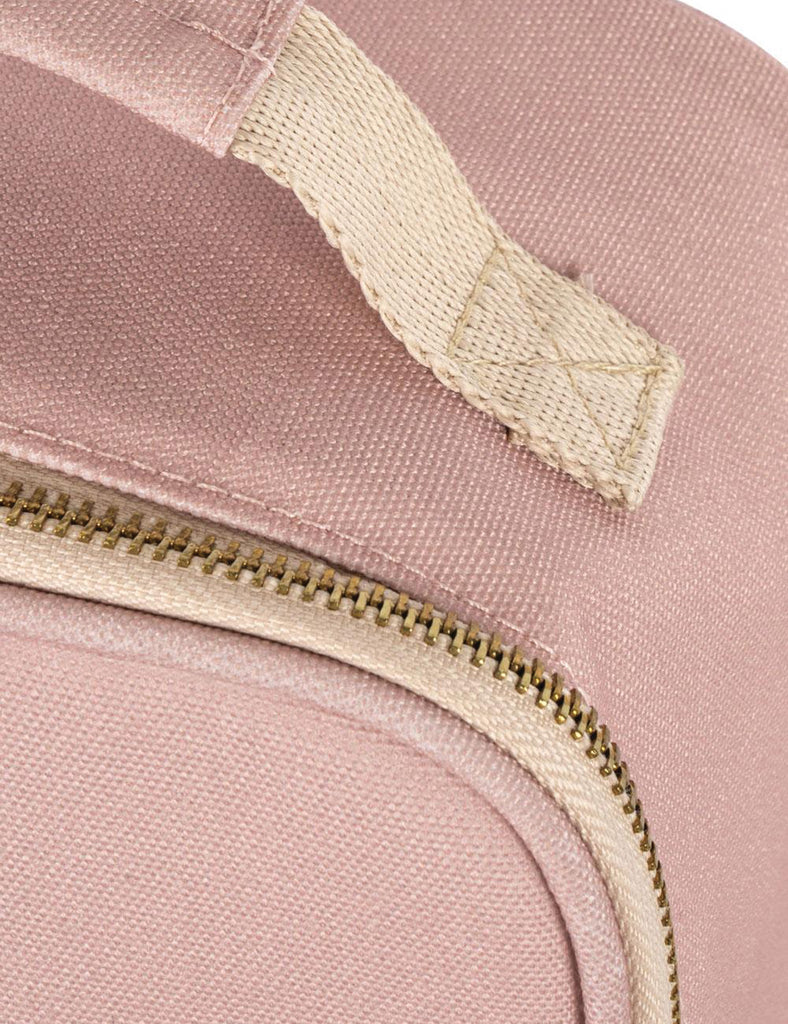Close-up of a pink bag with a gold zipper and white label.