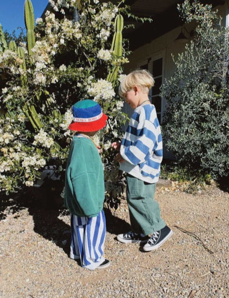 Two children standing outdoors near a cactus plant with white flowers.