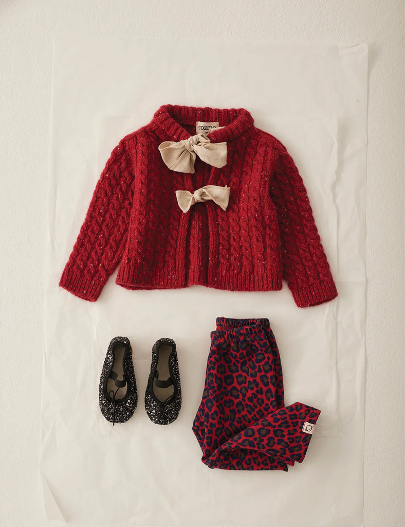 Red knitted cardigan with bows, leopard print pants, and black shoes on a white background