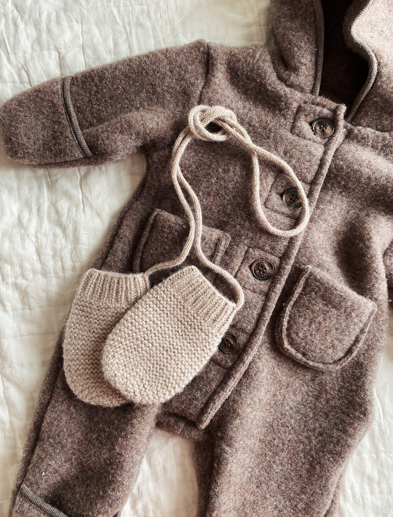 Brown coat with knitted baby booties on a white surface