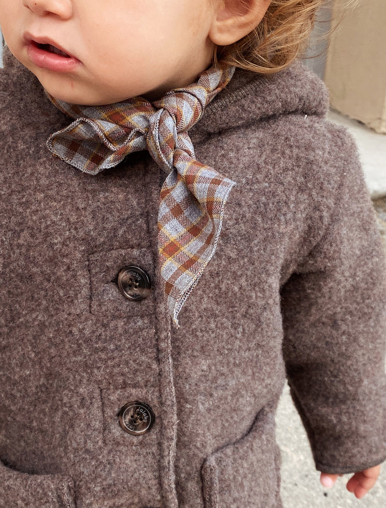Close-up of a child wearing a brown coat with a plaid scarf