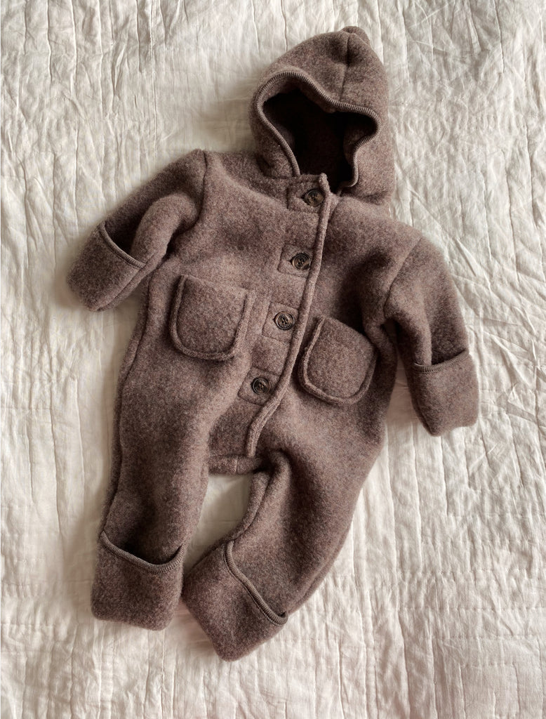 Brown baby snowsuit with buttons on a textured white surface
