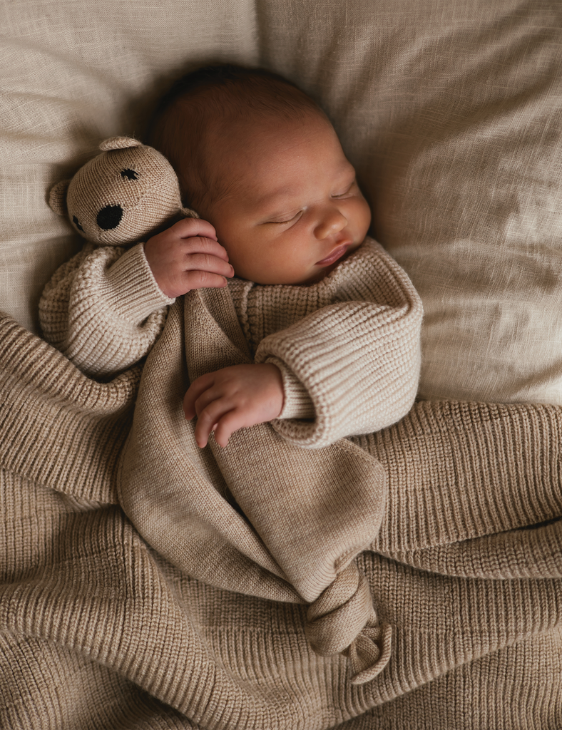 Close up of newborn baby snuggling a stuffed bear.