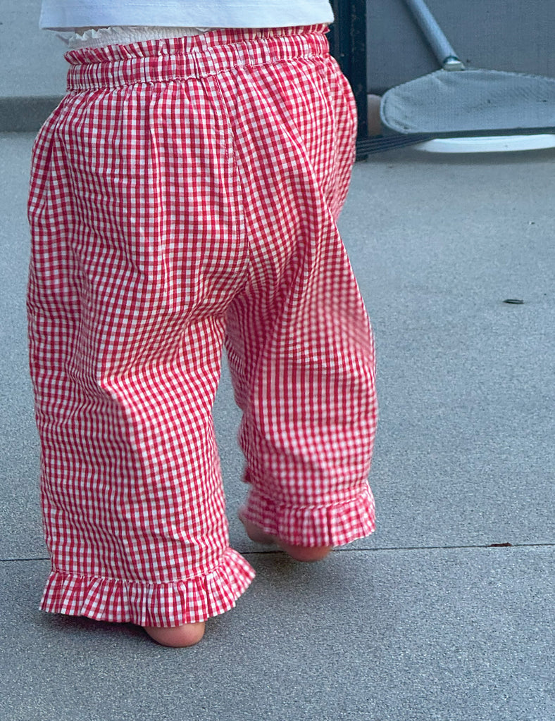 Red and white checkered pants on a child standing on a concrete surface.