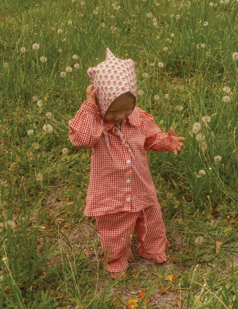 Image of a little girl wearing a red and white check outfit in a field