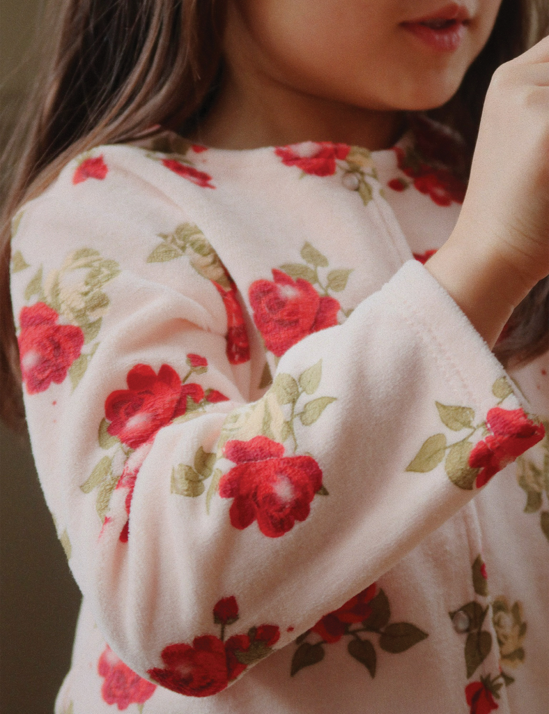 Close-up of a person wearing a floral sweater with red roses on a beige background