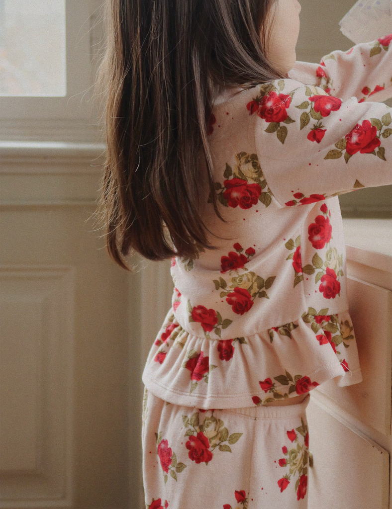 Child wearing a floral outfit standing indoors.