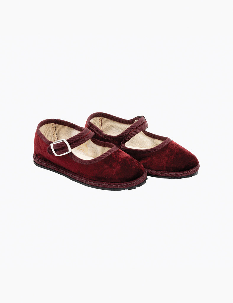Pair of maroon velvet shoes with a buckle on a white background