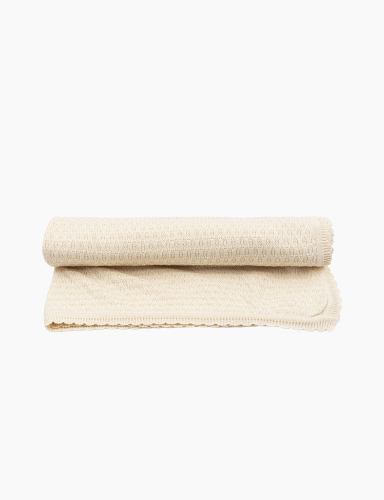 Folded beige blanket on a white background
