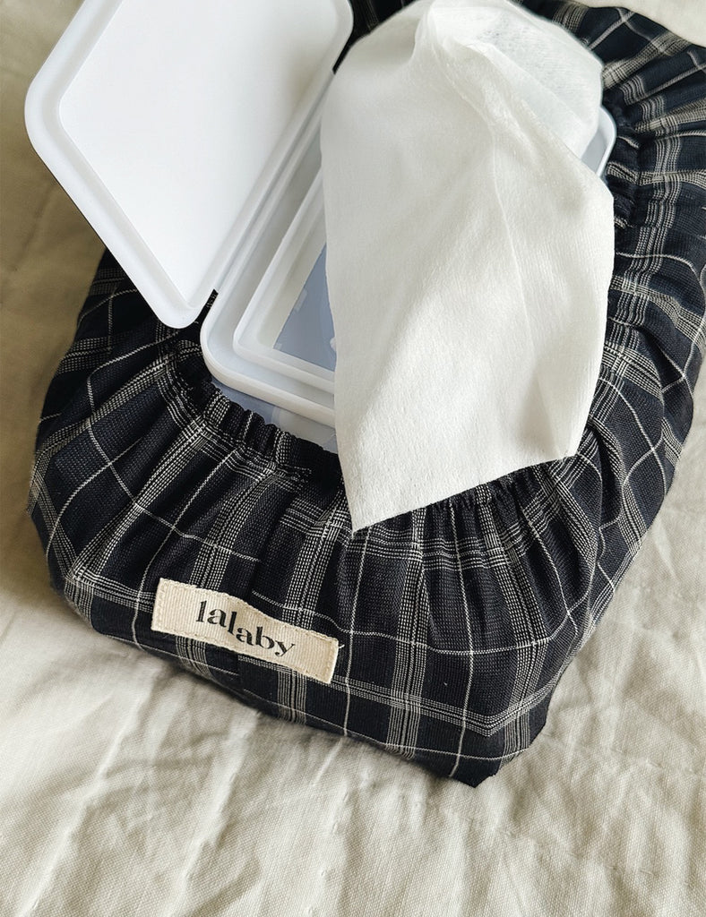 Black plaid car seat cover with a white label on a beige surface