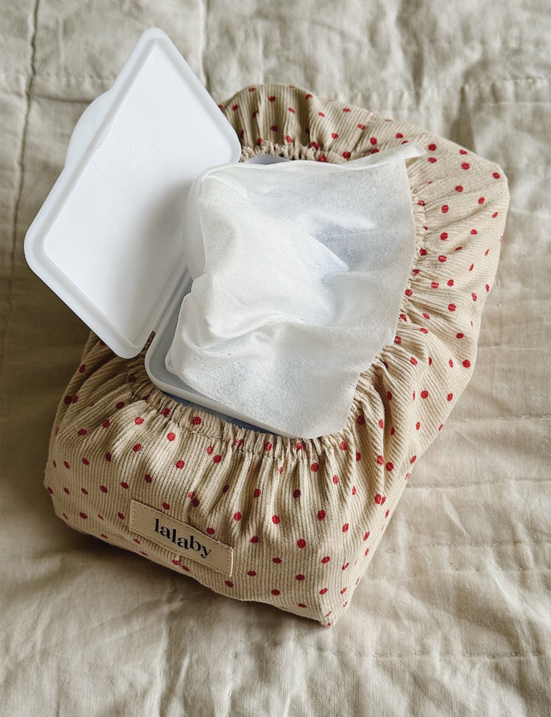 Lalaby baby wipes container with a white lid on a beige fabric background