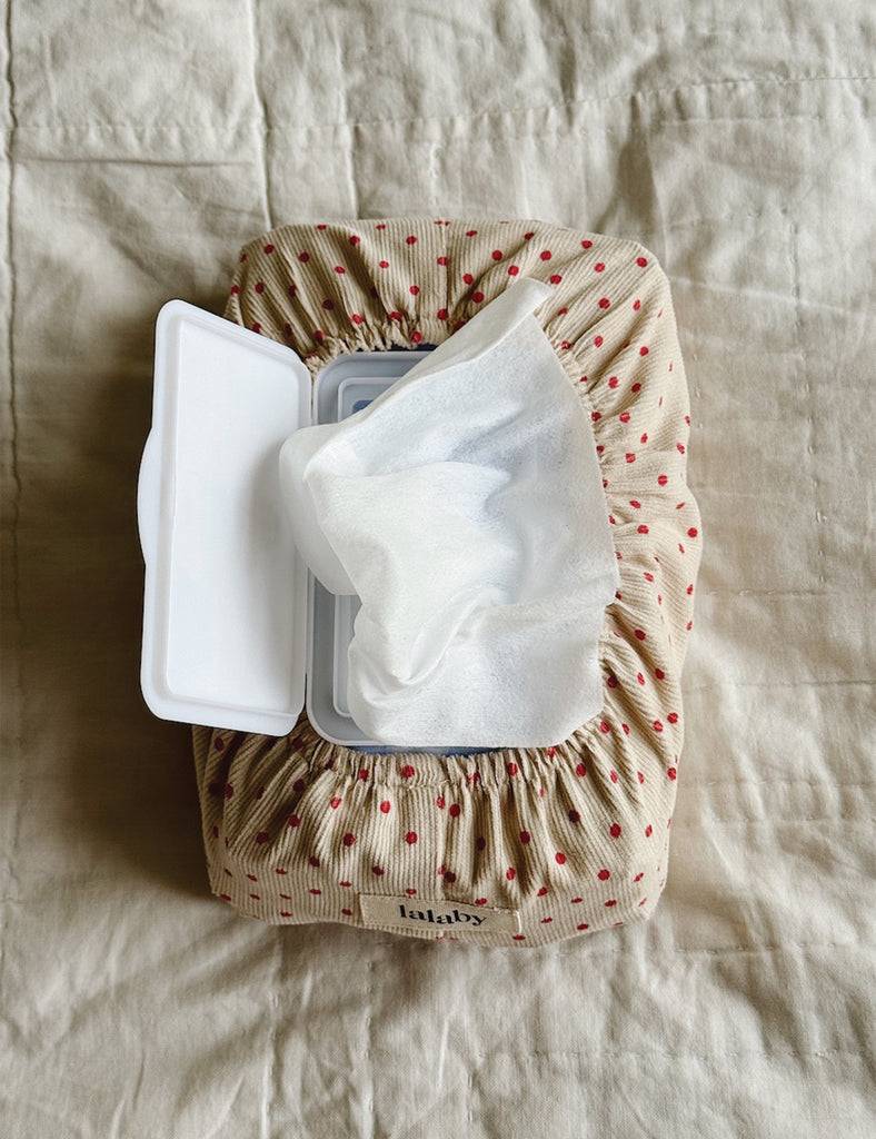 Wipe container with lid open on a textured beige fabric background