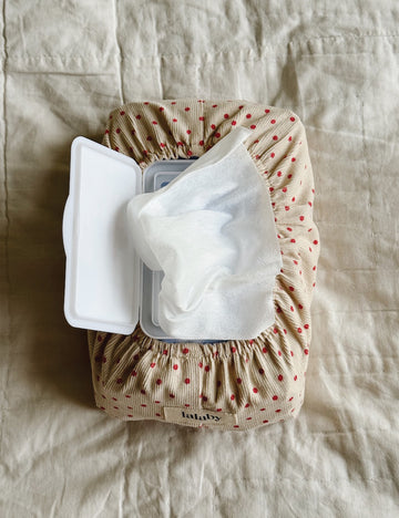 Wipe container with lid open on a textured beige fabric background