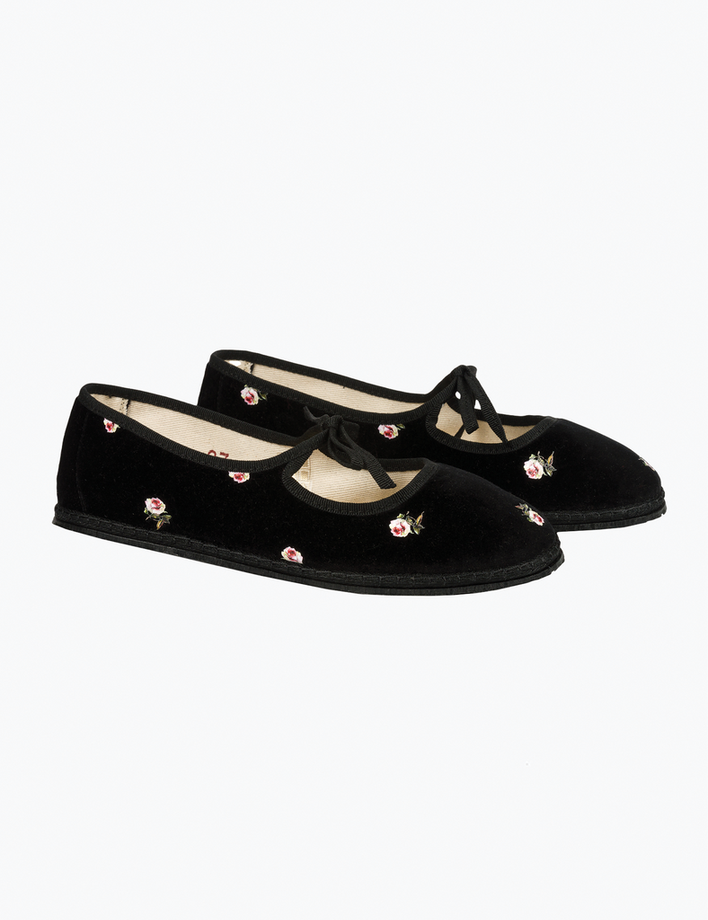 Black velvet shoes with decorative elements on a white background