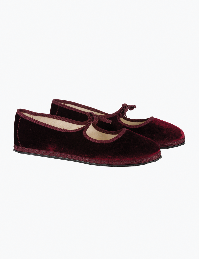 Pair of maroon velvet slippers on a white background